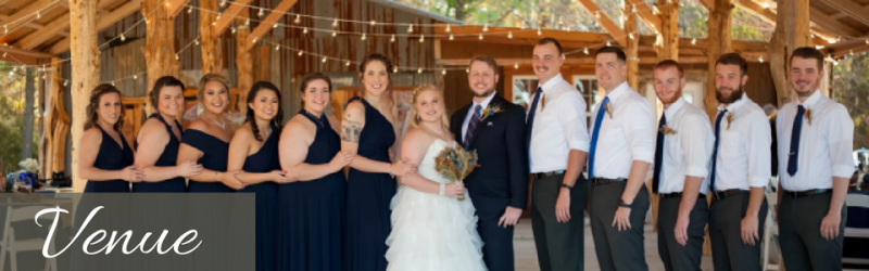 Wedding party posing in a rustic venue, with bride in white and attendants in navy dresses and white shirts