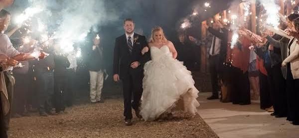 Bride and groom walk under sparklers at a nighttime wedding celebration