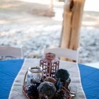 Decorative lanterns and berries on a table with a blue cloth in a bright outdoor setting