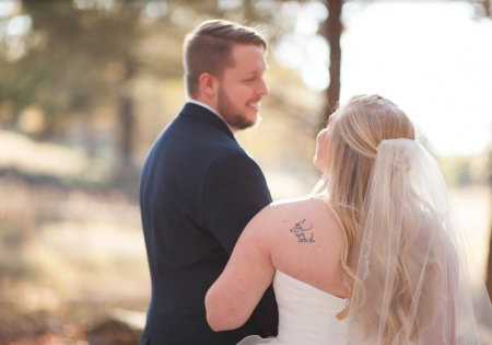 Couple in wedding attire embracing outdoors in warm sunlight