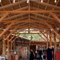 Rustic timber hall with exposed beams and a few people standing near the back wall