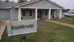 Williams-Lord Funeral Home with gray building, white columns, and sign in front