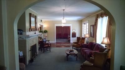 Spacious living room with red sofa, fireplace, large windows, and arched doorway