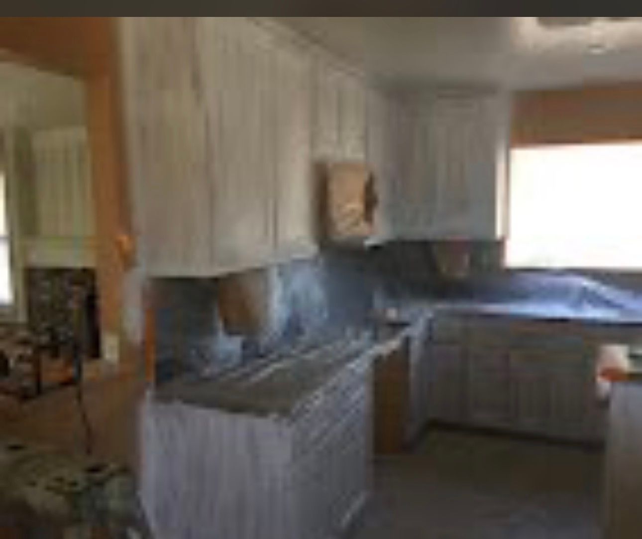 Blurry kitchen with white cabinets, dark countertops, and a window above the sink