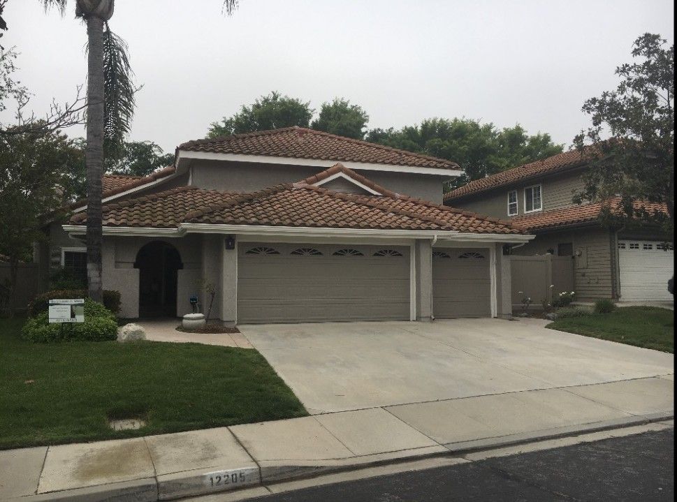 Suburban house with a tiled roof, two-car garage, and driveway on a quiet street.