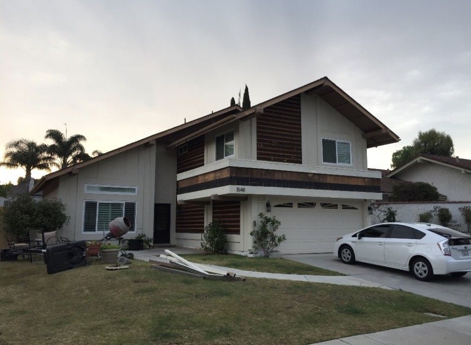 Suburban two-story house with white car parked in the driveway at dusk