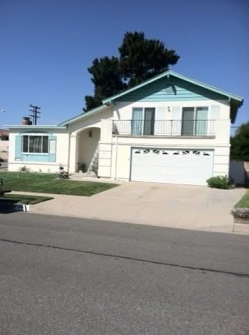 Suburban house with white garage, light blue roof trim, driveway, and clear blue sky