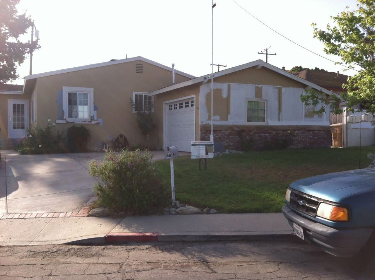 Suburban house with a driveway, front yard, mailbox, and a car at the curb.