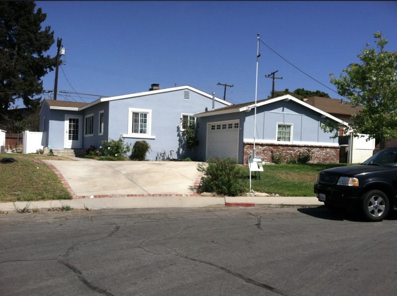 Residential house with driveway and parked SUV on a sunny suburban street