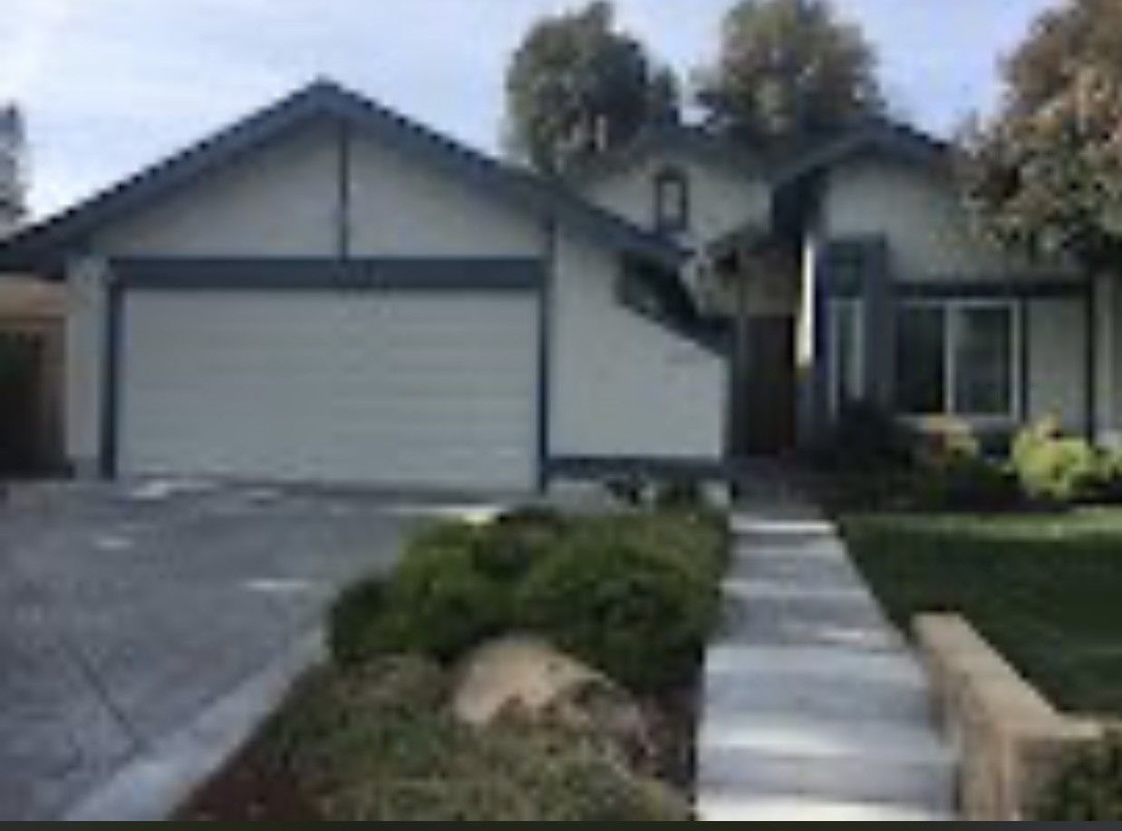 Suburban house with a garage, front walkway, and trimmed bushes at the entrance