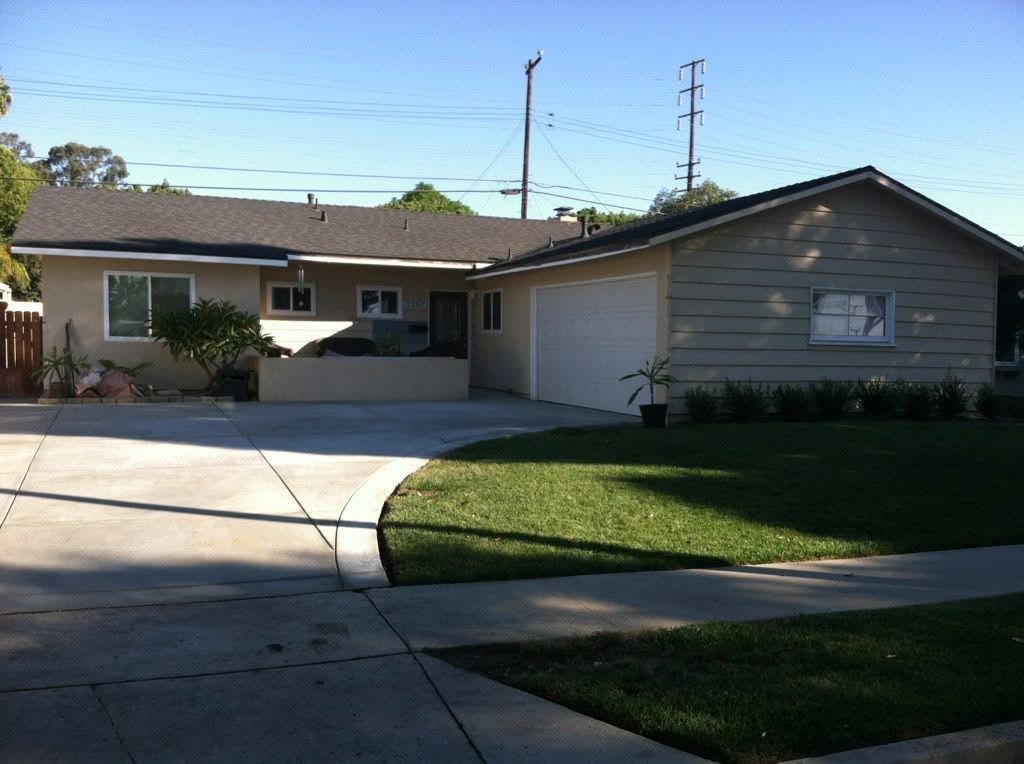 Suburban single-story house with a driveway, garage, and green lawn in front