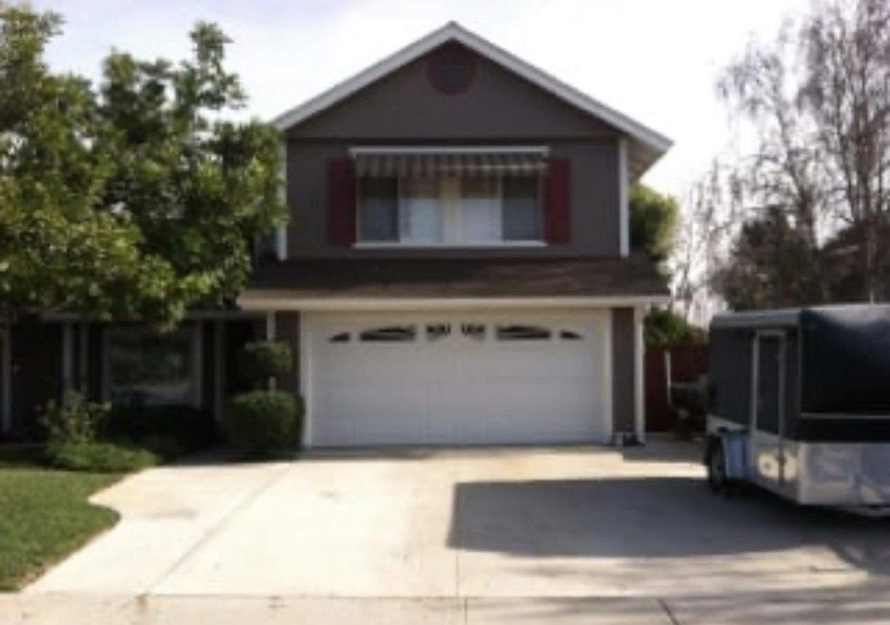 Two-story suburban house with a garage driveway and a parked RV on the right