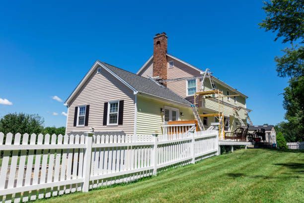White house with a red brick chimney, white picket fence, and green lawn under a bright blue sky