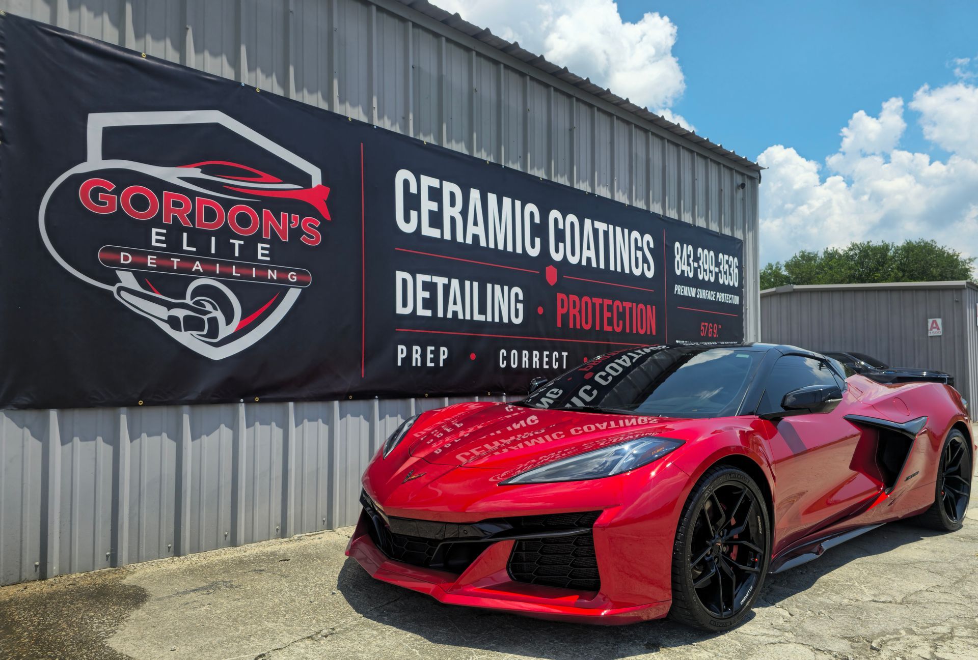 Red sports car parked beside Gordon’s detailing shop and ceramic coatings sign