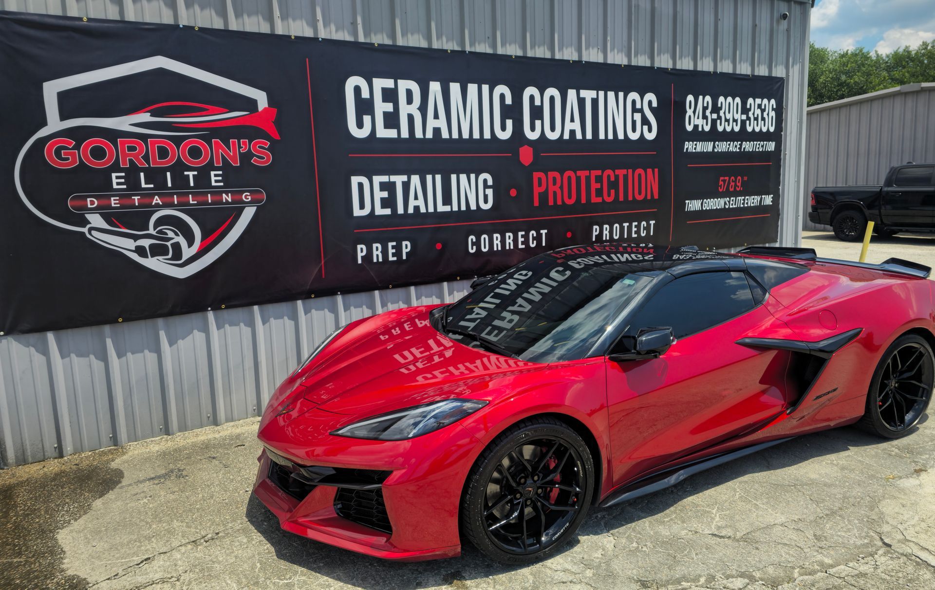 Red sports car parked outside Gordon’s Elite ceramic coatings and detailing shop