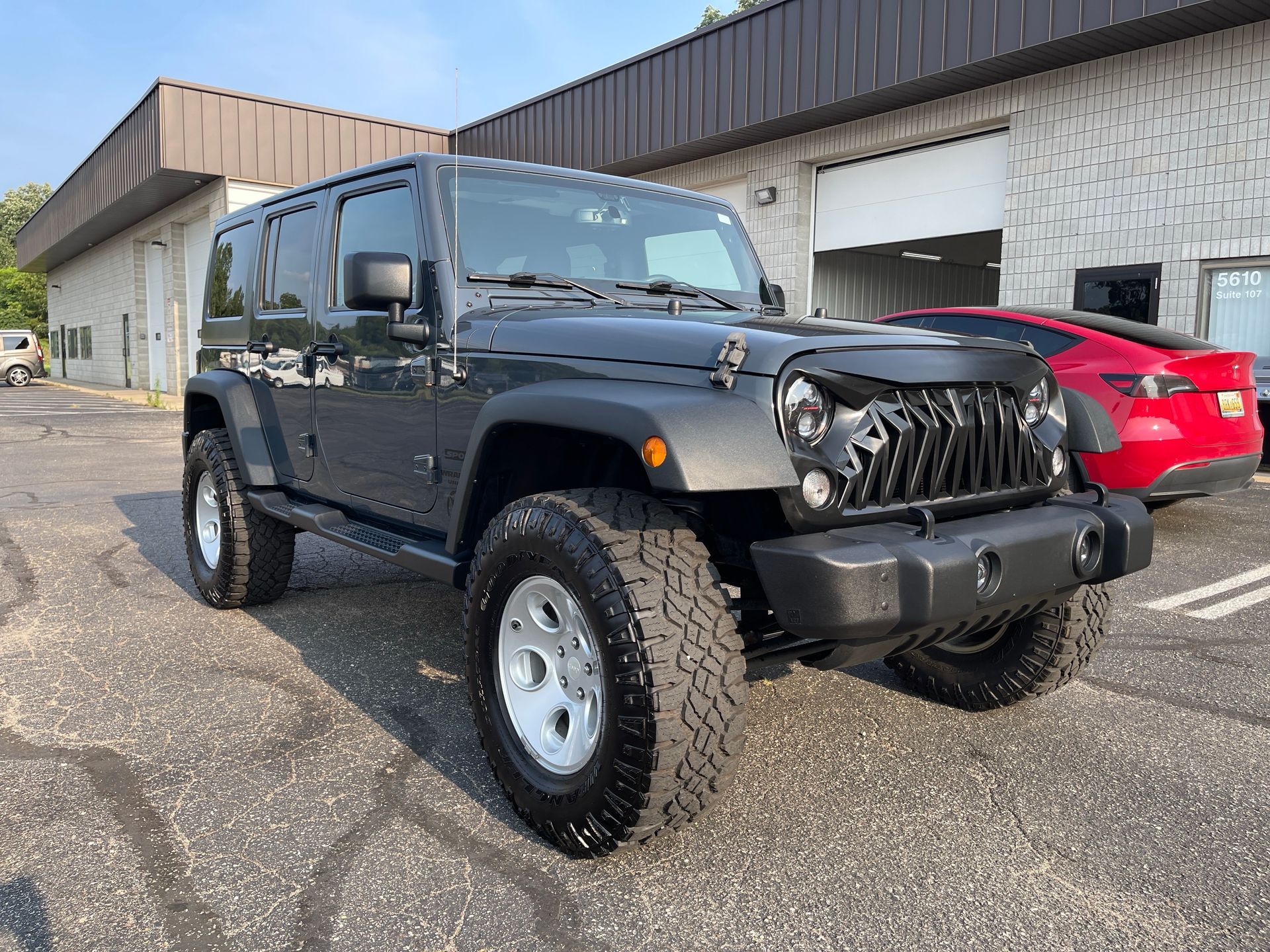 A black jeep wrangler is parked in front of a building.