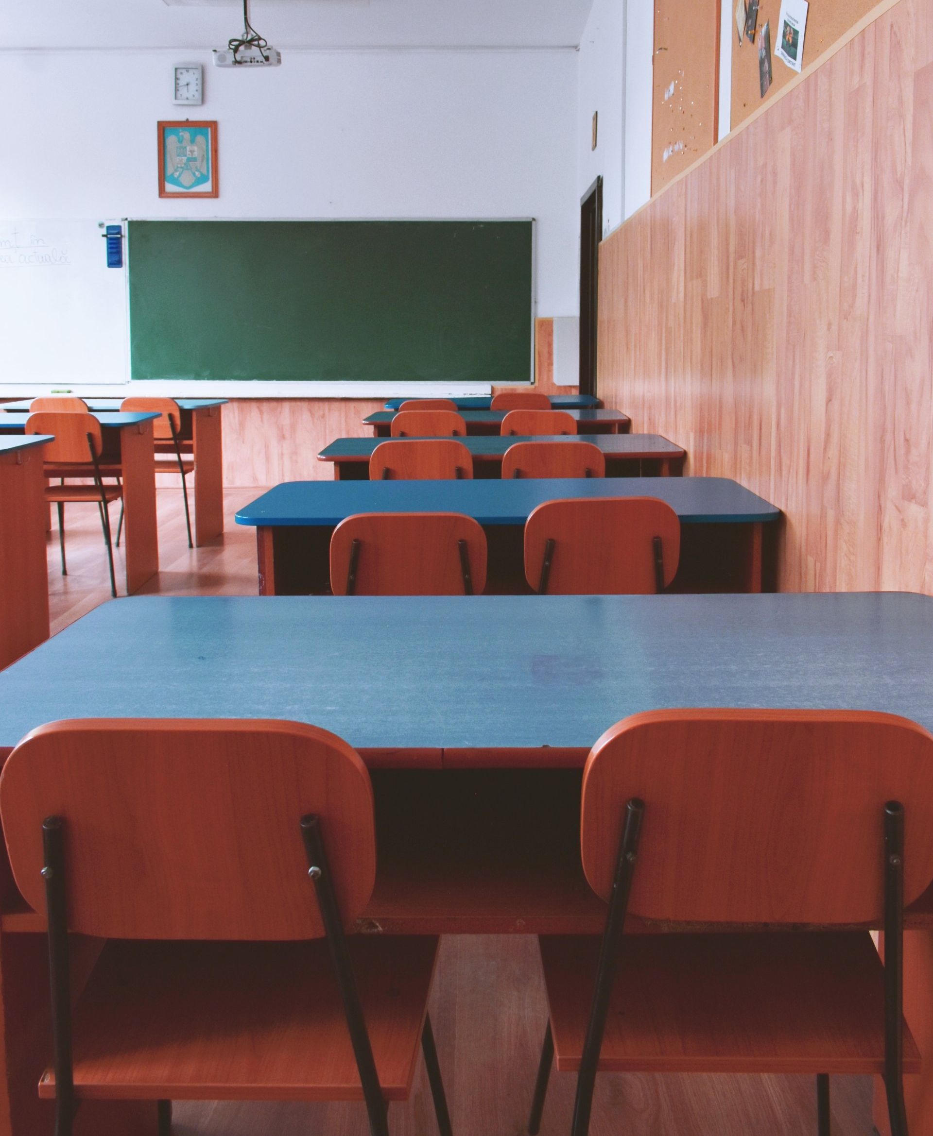 An empty classroom with blue tables and chairs