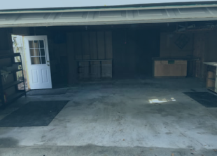 An empty garage with a white door and a concrete floor