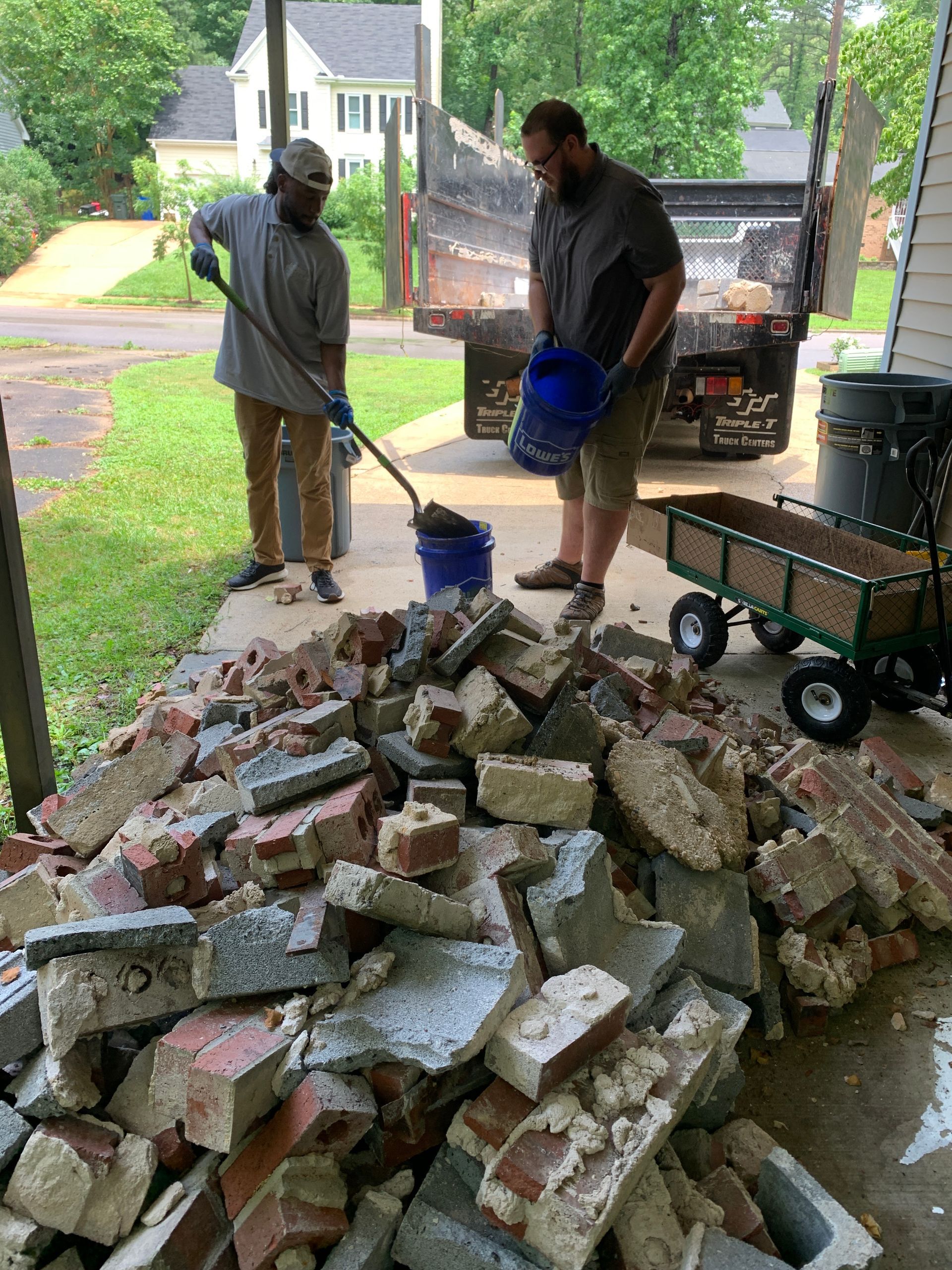 Two men are standing next to a pile of bricks.