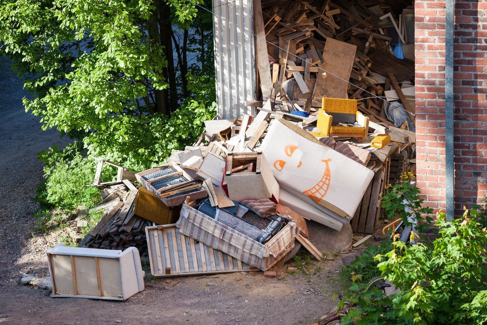 Pile of debris including boxes, boards, and other discarded items in front of a building.