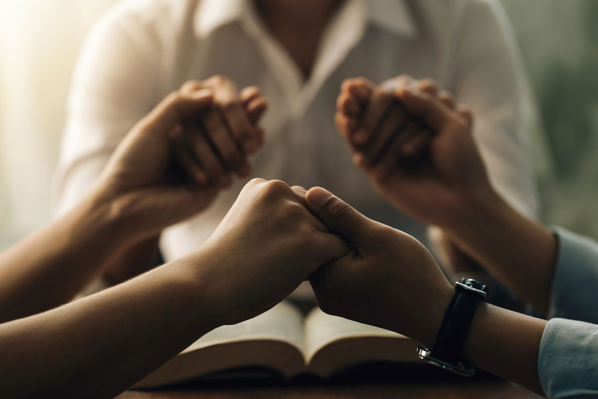 Two people are holding hands over an open bible.