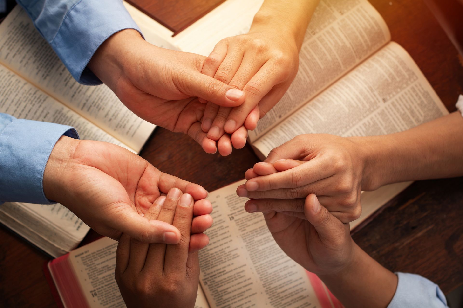 A group of people are holding hands in front of a bible.