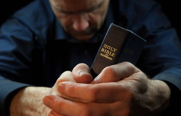 A man is holding a holy bible in his hands