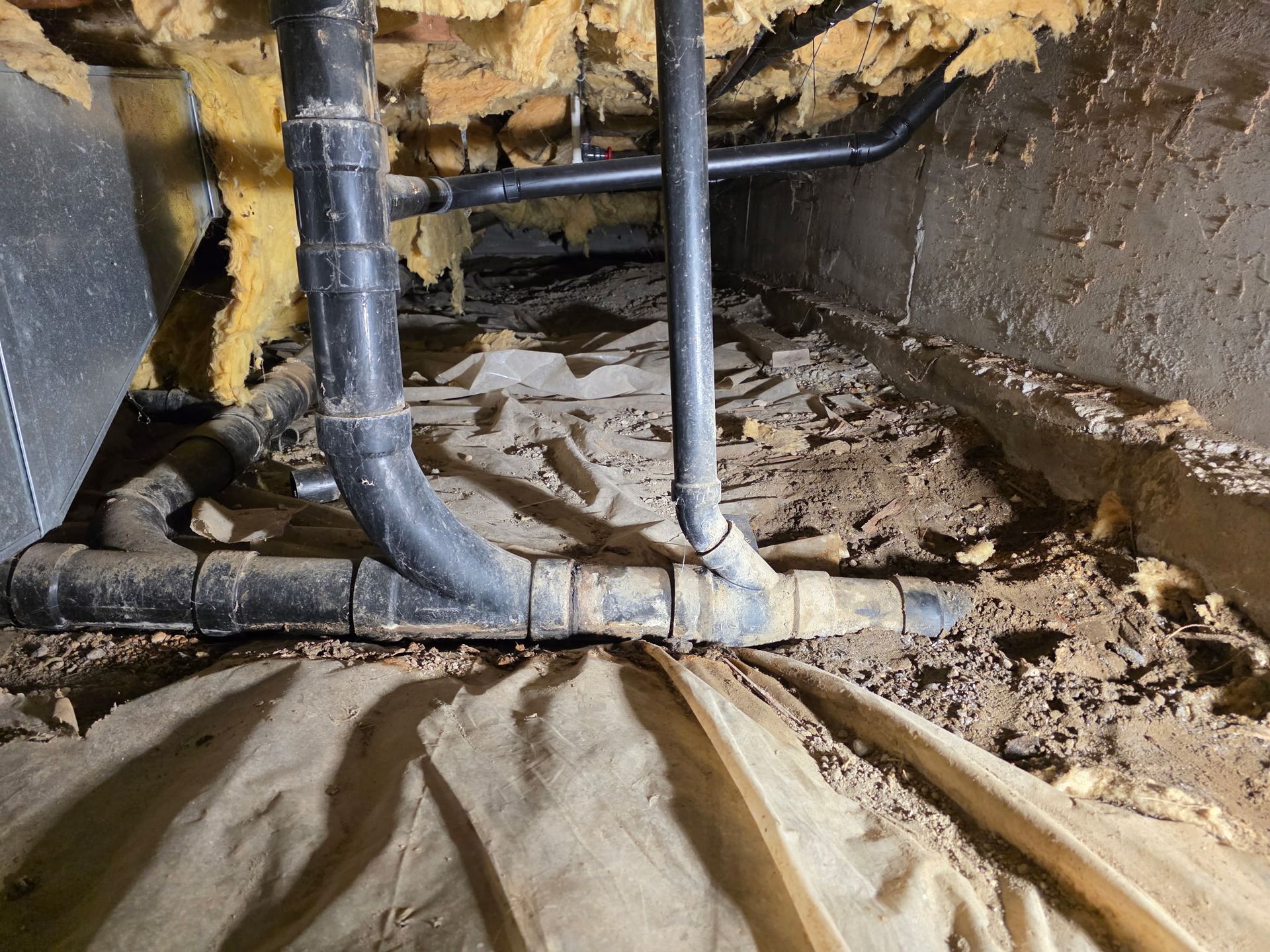 Gray pipes run along a concrete wall, turning sharply at the corner.
