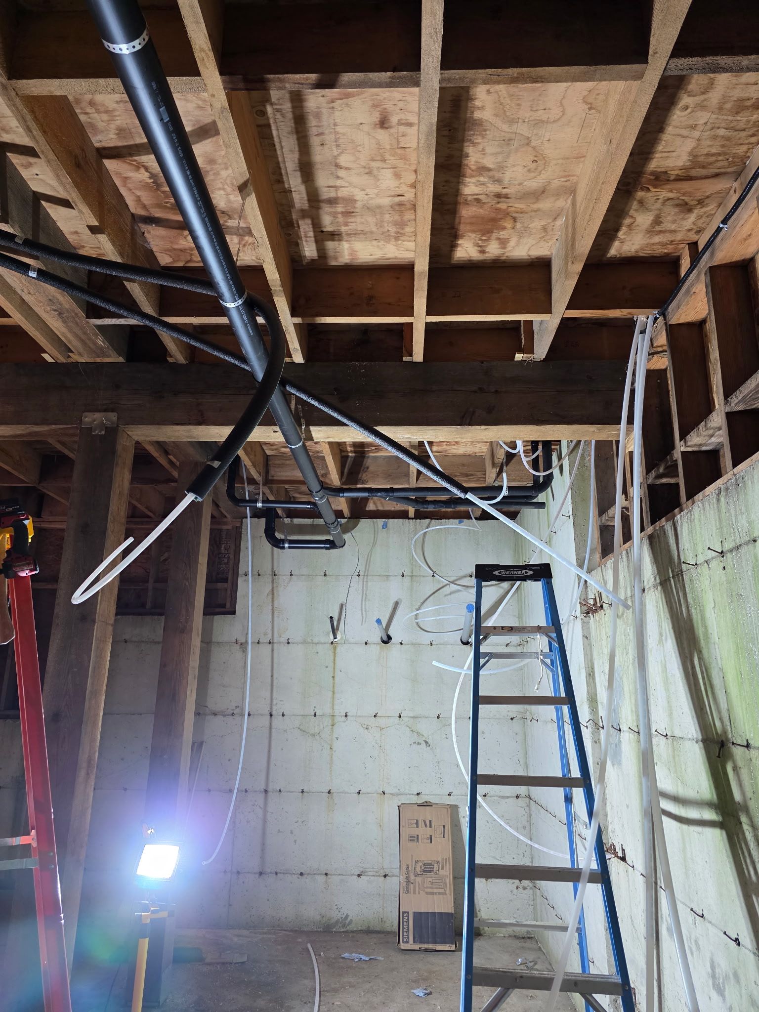 Gray pipes run along a concrete wall, turning sharply at the corner.