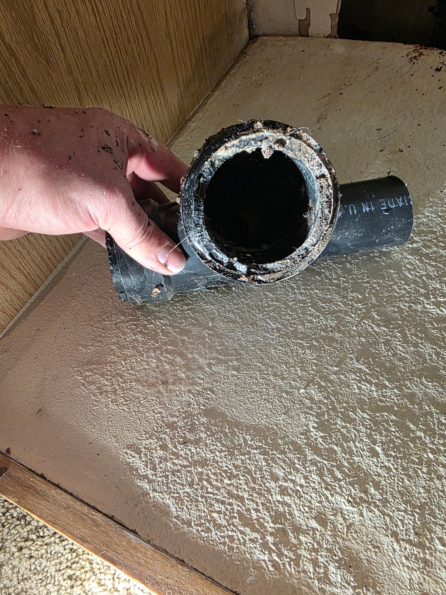 Gray pipes run along a concrete wall, turning sharply at the corner.