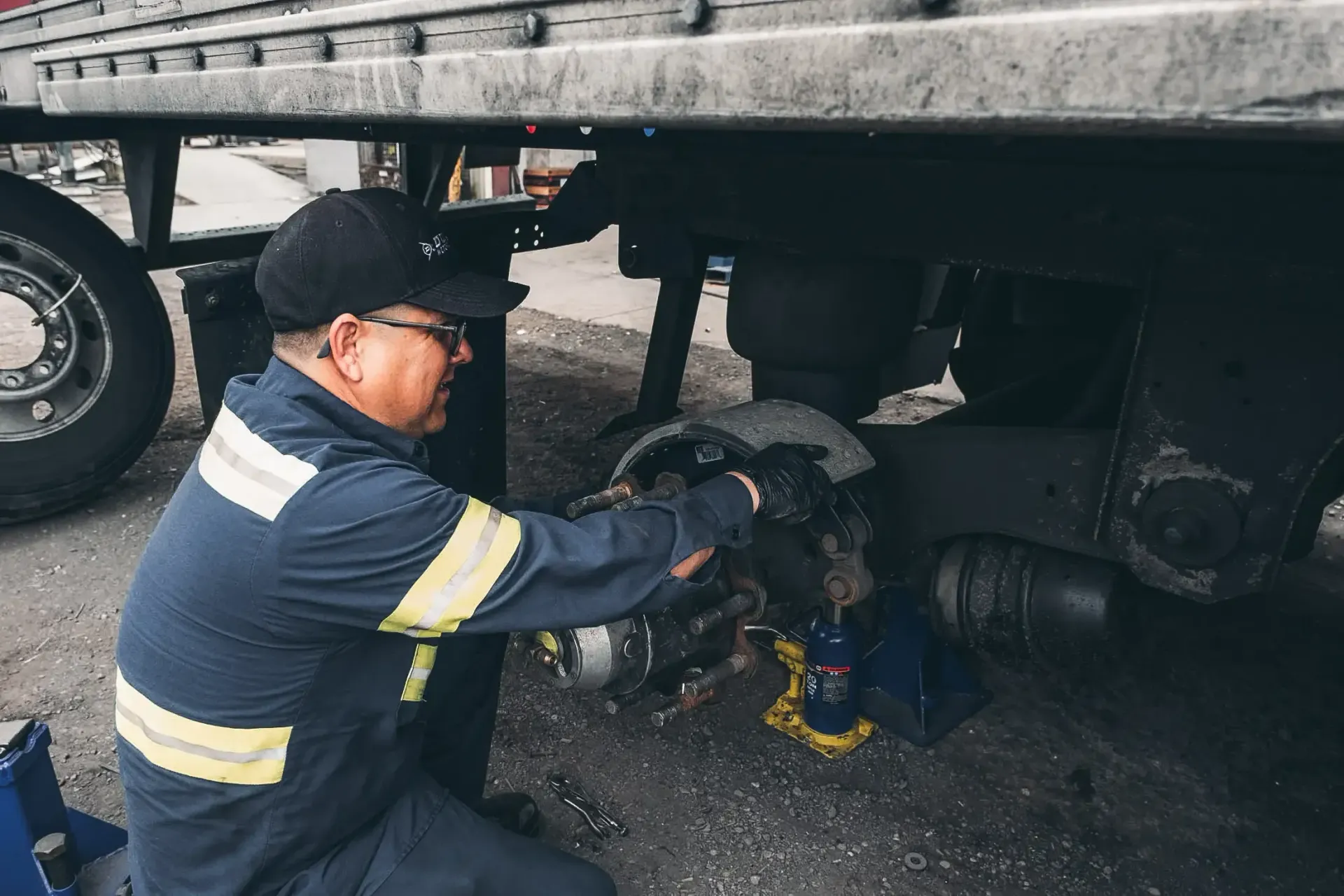 A man is working on the underside of a truck.