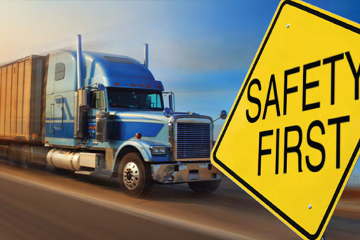 A blue semi truck is driving down a highway next to a safety first sign.