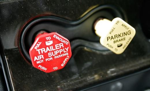 A red trailer air supply button is next to a white parking brake button