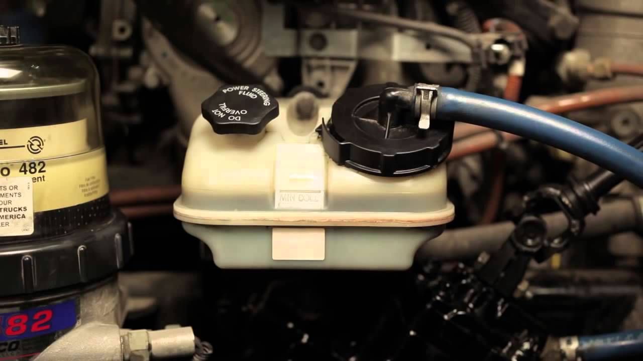 A close up of a car engine with a hose attached to it