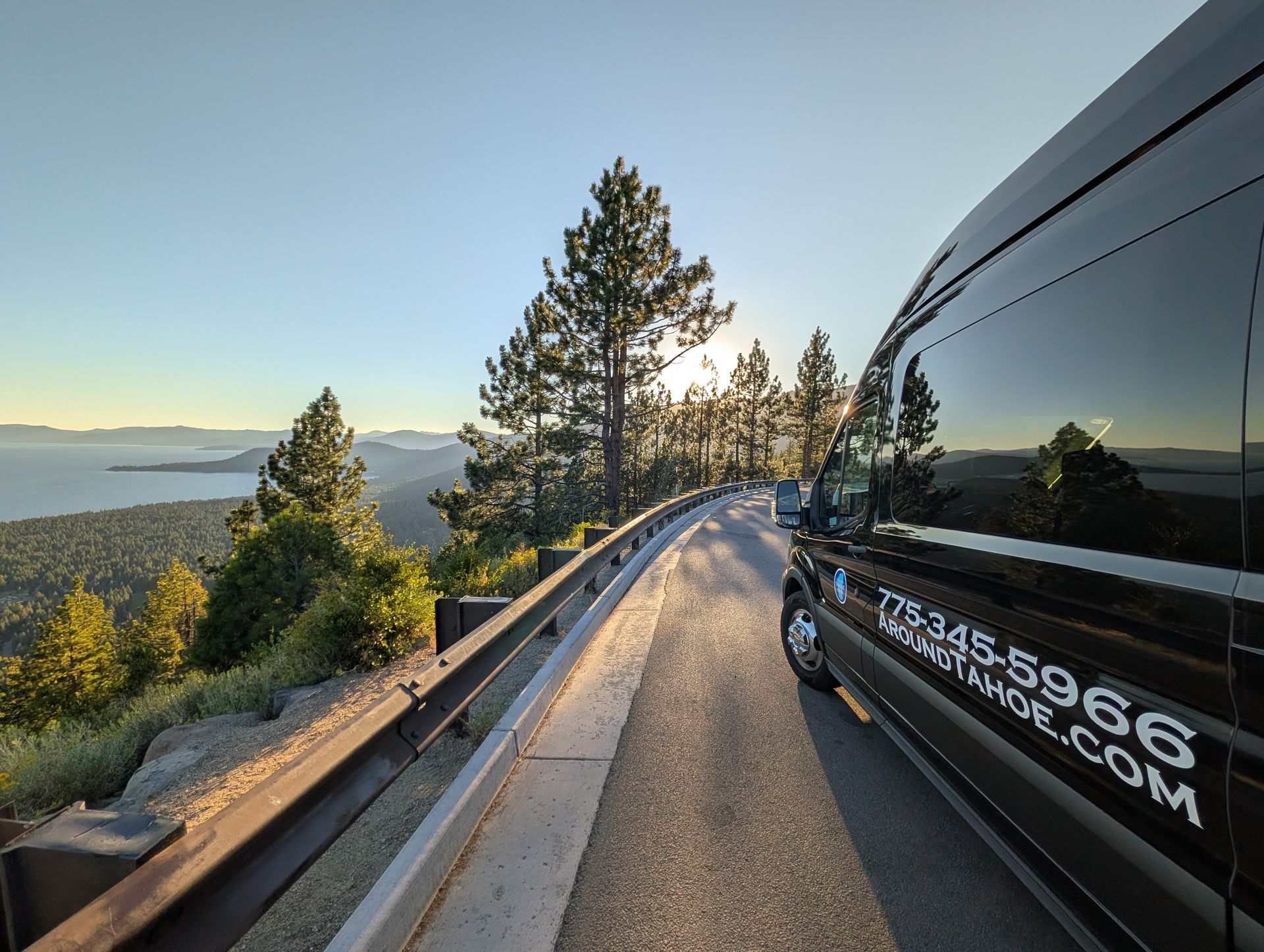 Around Tahoe Tours van at a Lake Tahoe overlook with mountains, pine trees, and the lake at sunset in Nevada