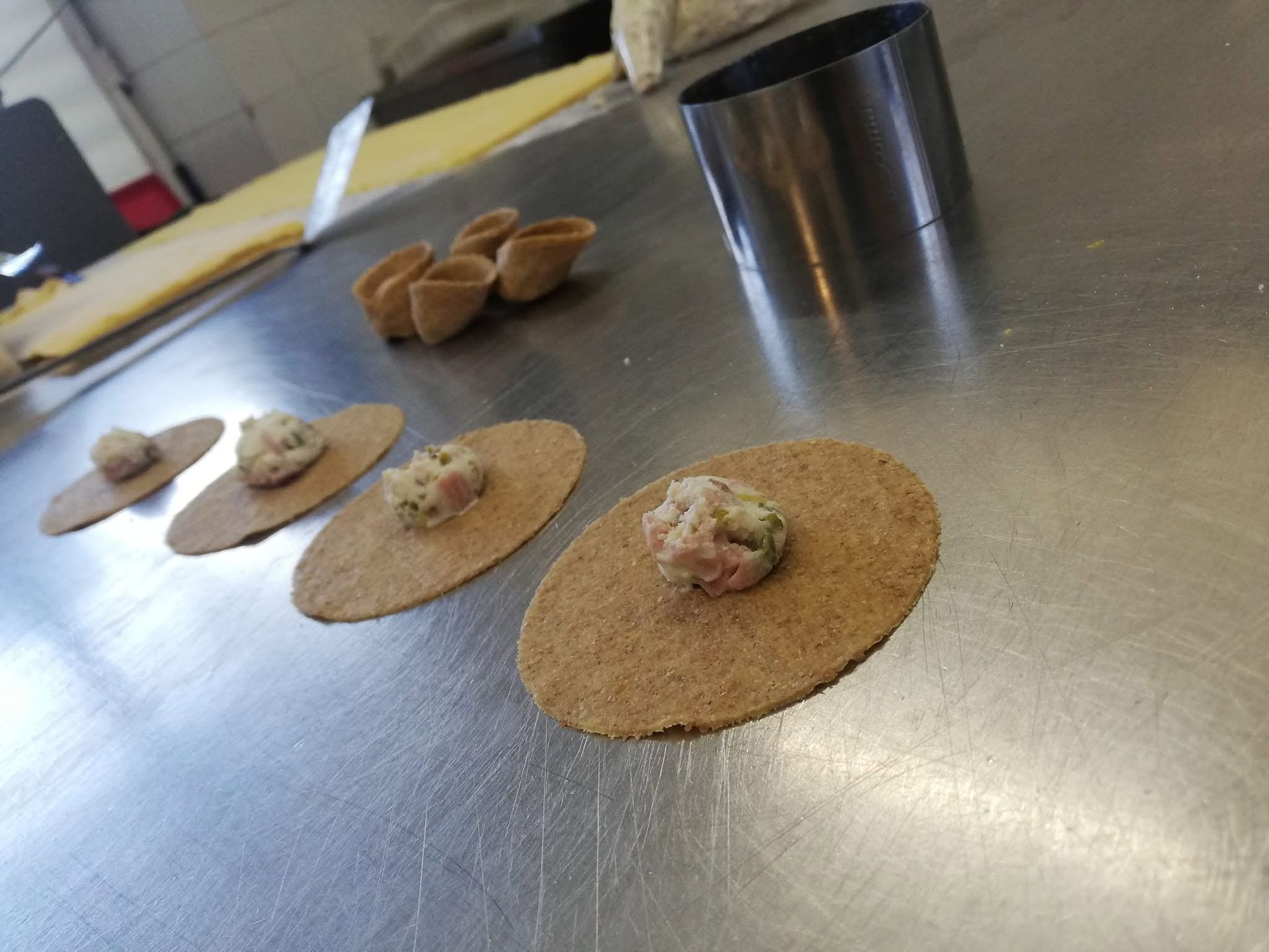 Tavolino in metallo con quattro piccole focaccine simili a tortillas, farcite, e una tazza sullo sfondo