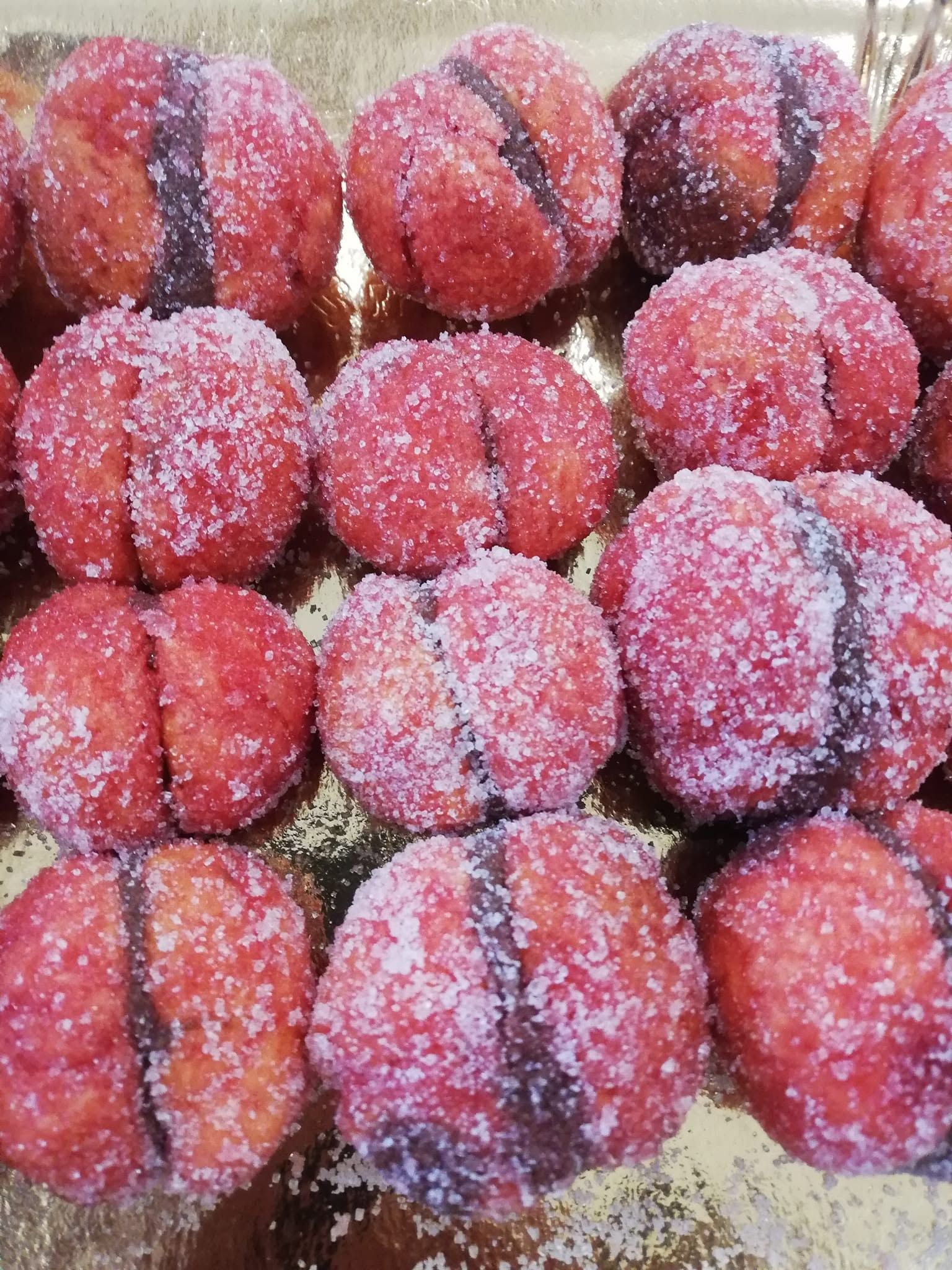 Cestino di prugne rosse spolverate di zucchero, disposte in file su un vassoio.