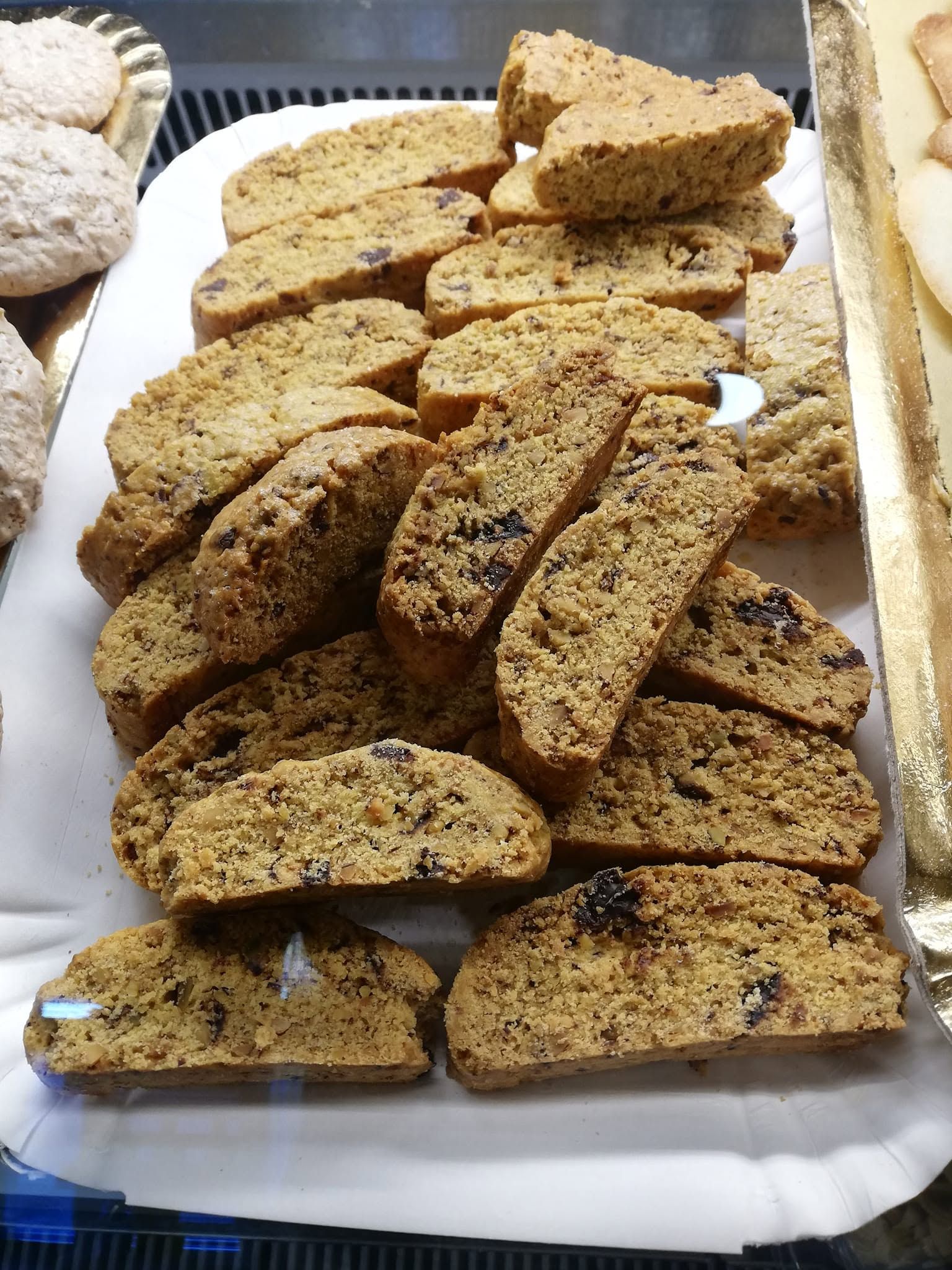 Vassoio di biscotti a fette su un piatto bianco, con alcuni biscotti spolverati di zucchero a velo accanto