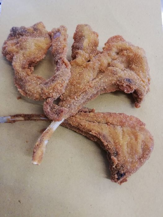 Salsa marrone in una ciotola con un cucchiaio su un bancone di metallo, con vassoi da buffet sullo sfondo