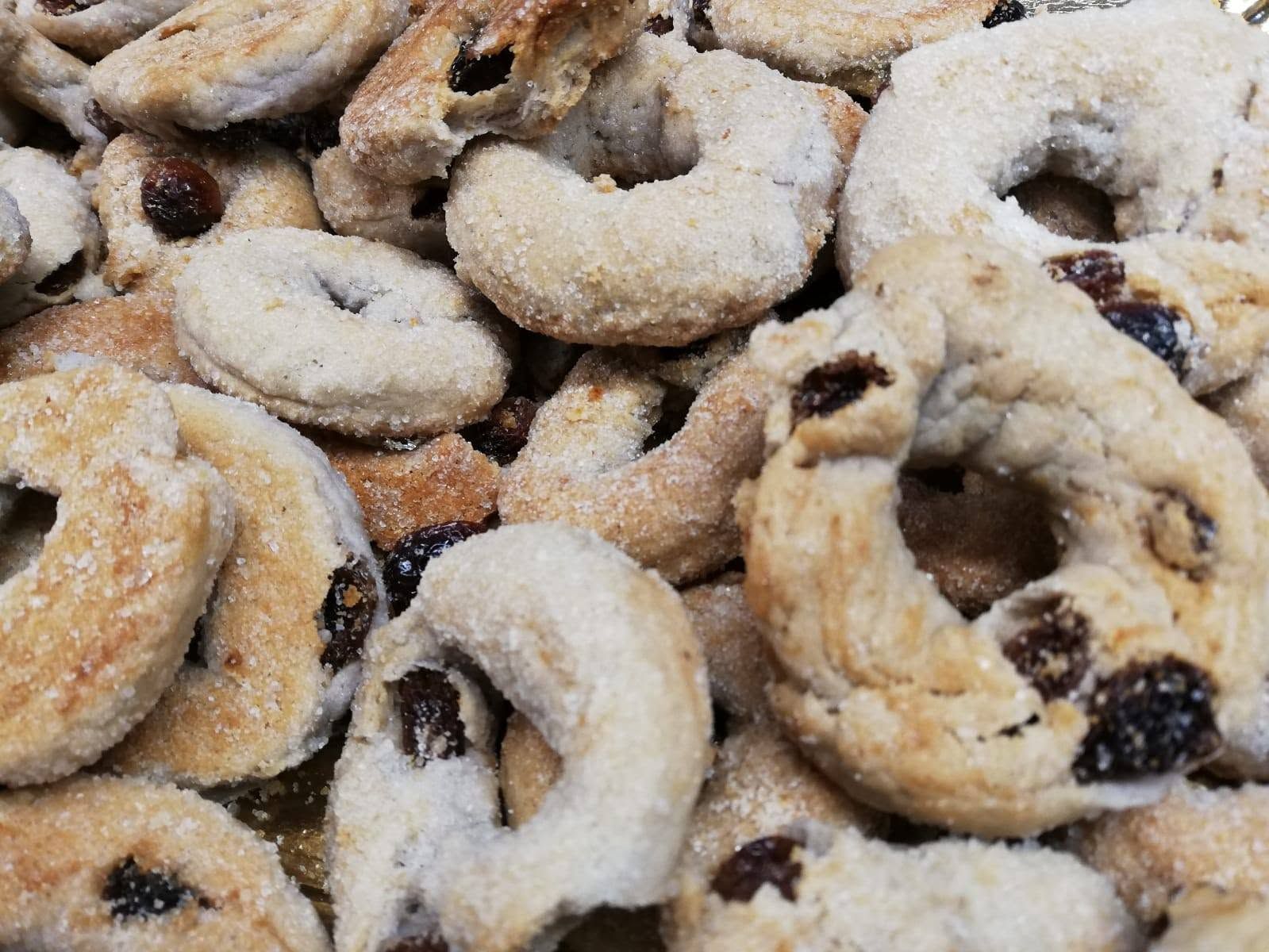Biscotti di pasta frolla con zucchero a velo e uvetta, disposti uno accanto all’altro