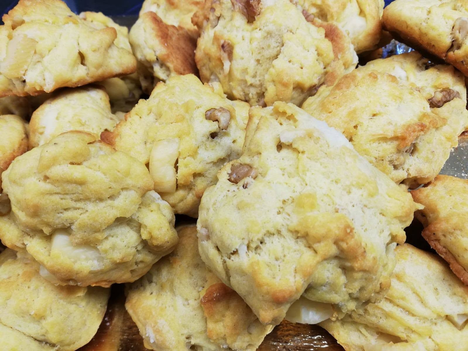 Vassoio di biscotti o scones fatti in casa, dorati e ammassati uno sull’altro, dalla consistenza friabile.