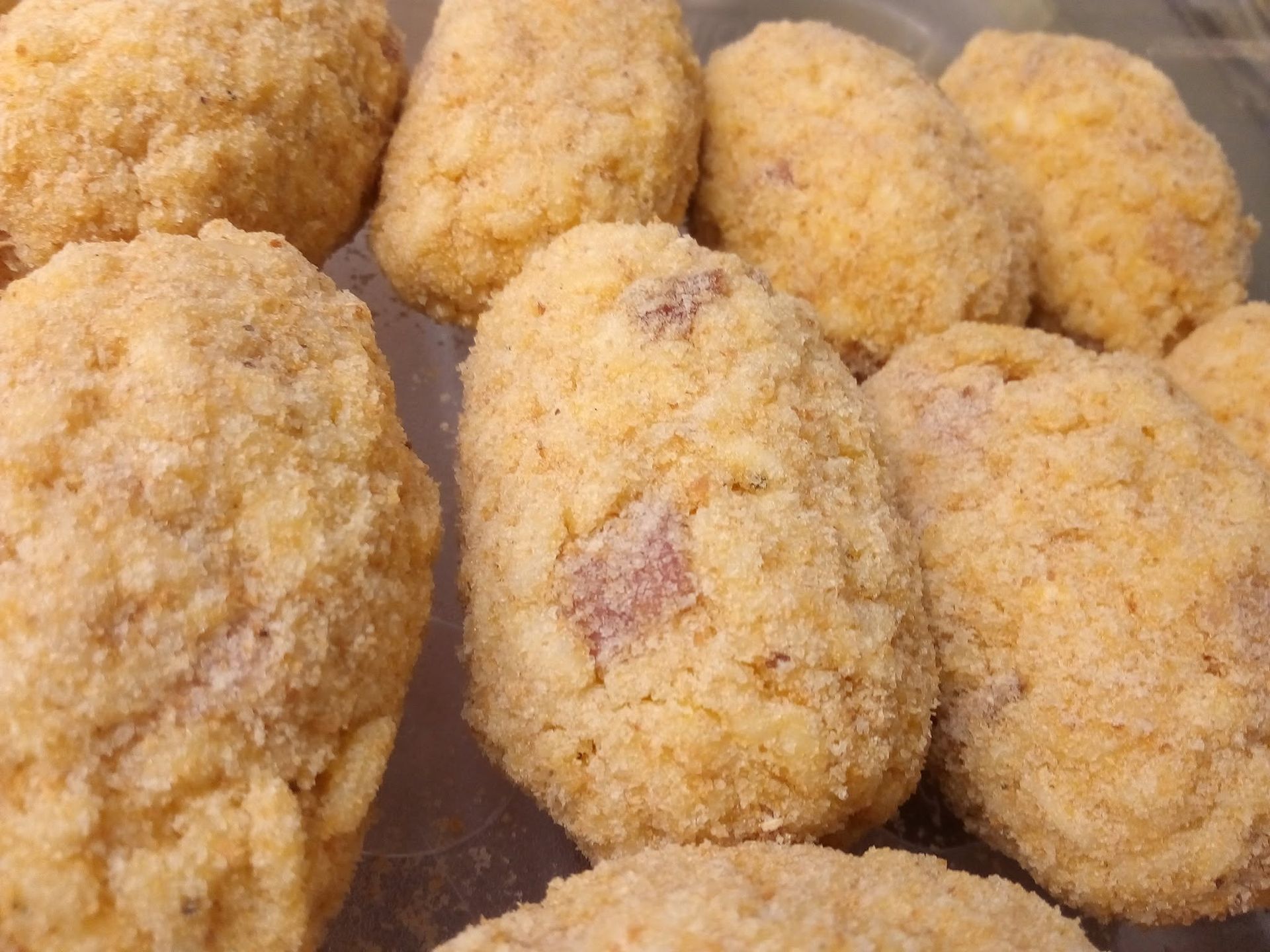 Bocconcini di pollo impanati disposti su un vassoio, dorati e pronti da cuocere