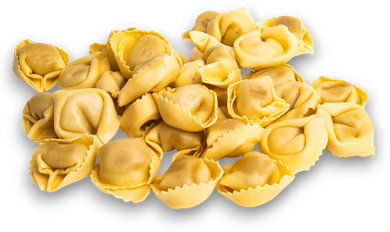 Mucchio di tortellini gialli crudi su sfondo bianco
