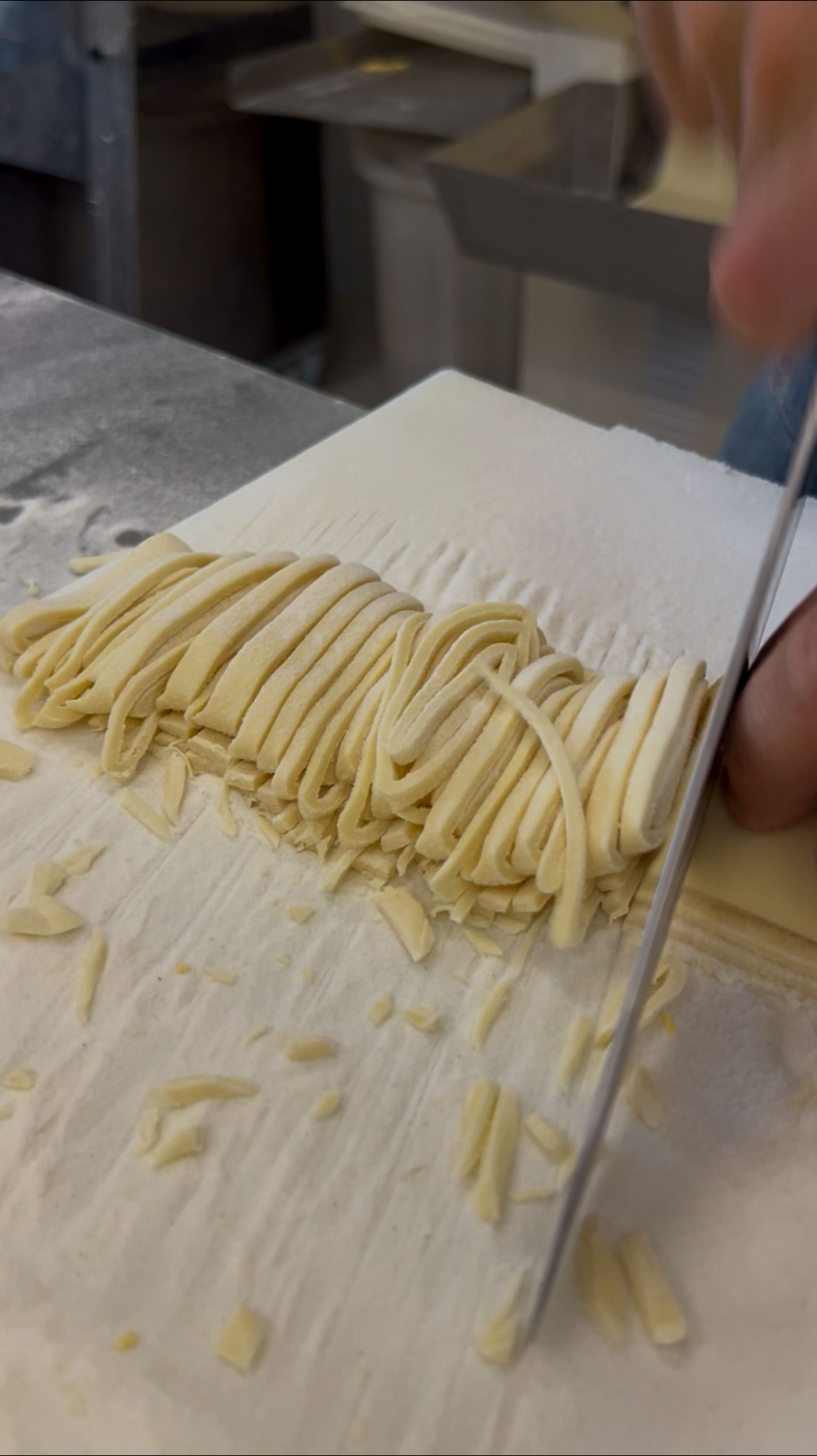 Pasta fresca tagliata a strisce su una spianatoia di legno infarinata