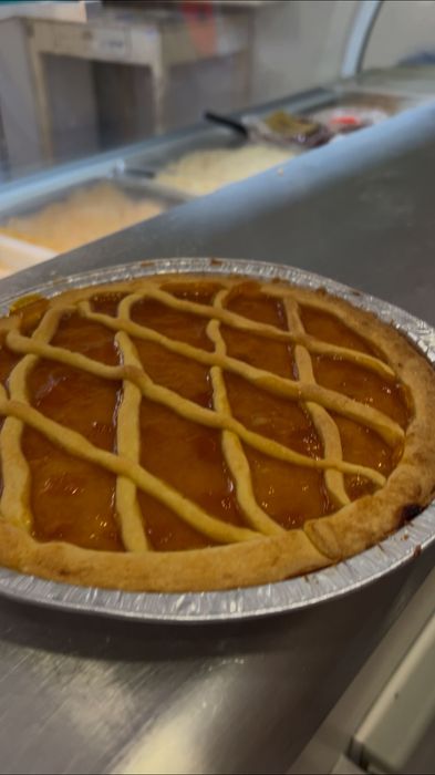 Crostata di frutta fresca con griglia decorativa, in una teglia di alluminio su un piano di lavoro in acciaio inox
