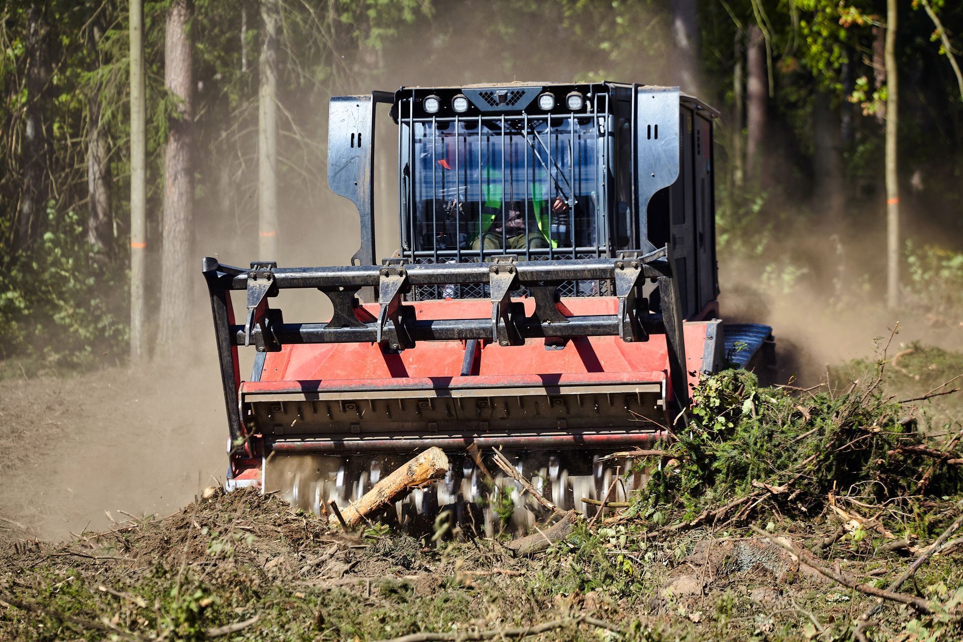 Heavy machinery mulching debris in a forest, creating a clearing.