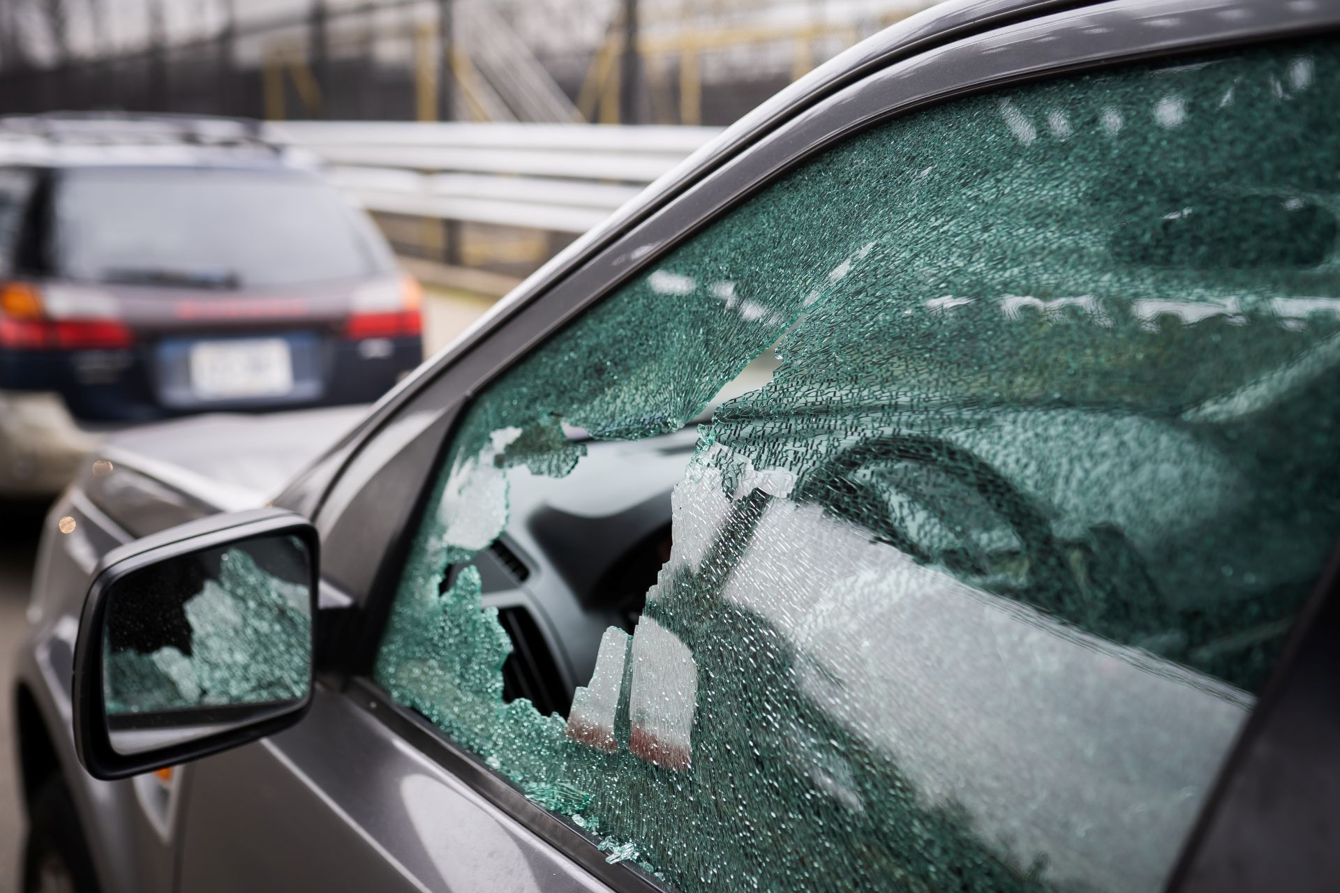 Broken car window, likely from a break-in, with shattered glass.