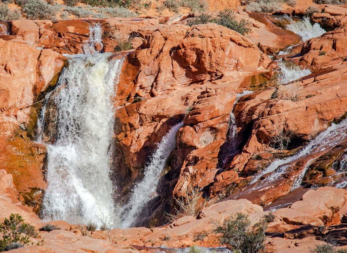 Waterfall flowing over red rocky cliffs in a desert landscape