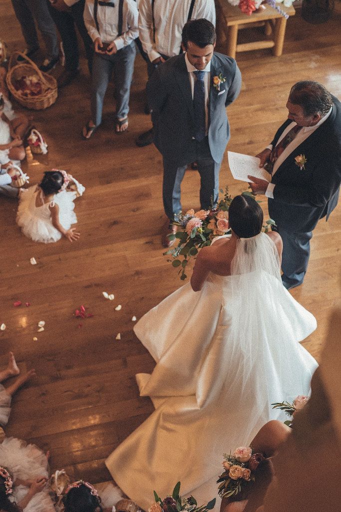 Wedding couple and officiant dancing on a wooden floor with petals scattered around them