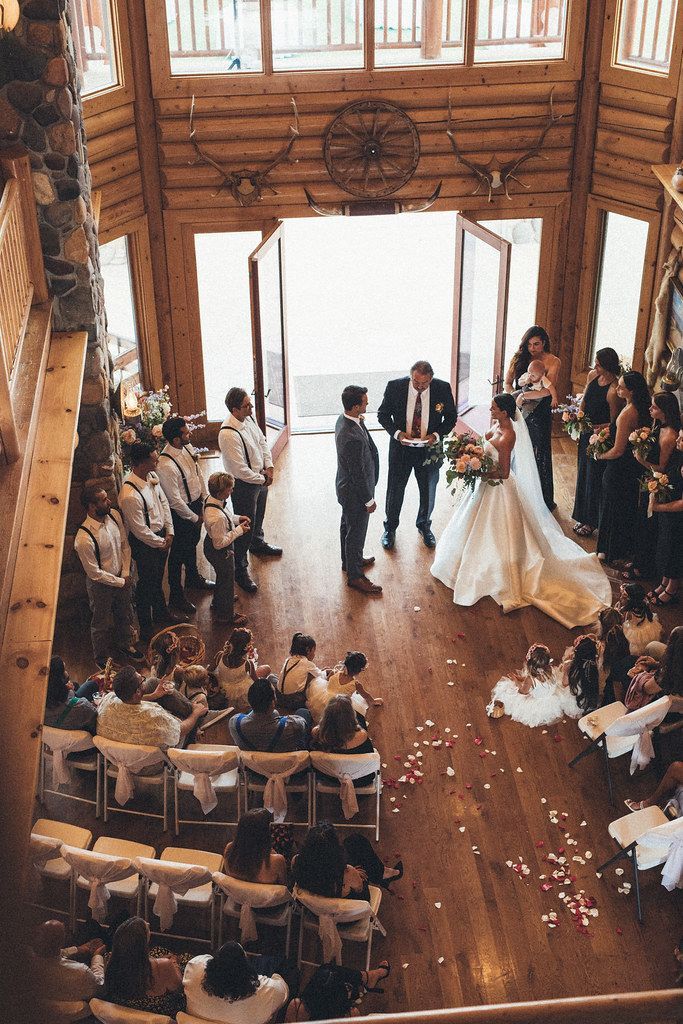 Wedding ceremony in a rustic lodge, couple at the altar as guests sit along a wooden aisle